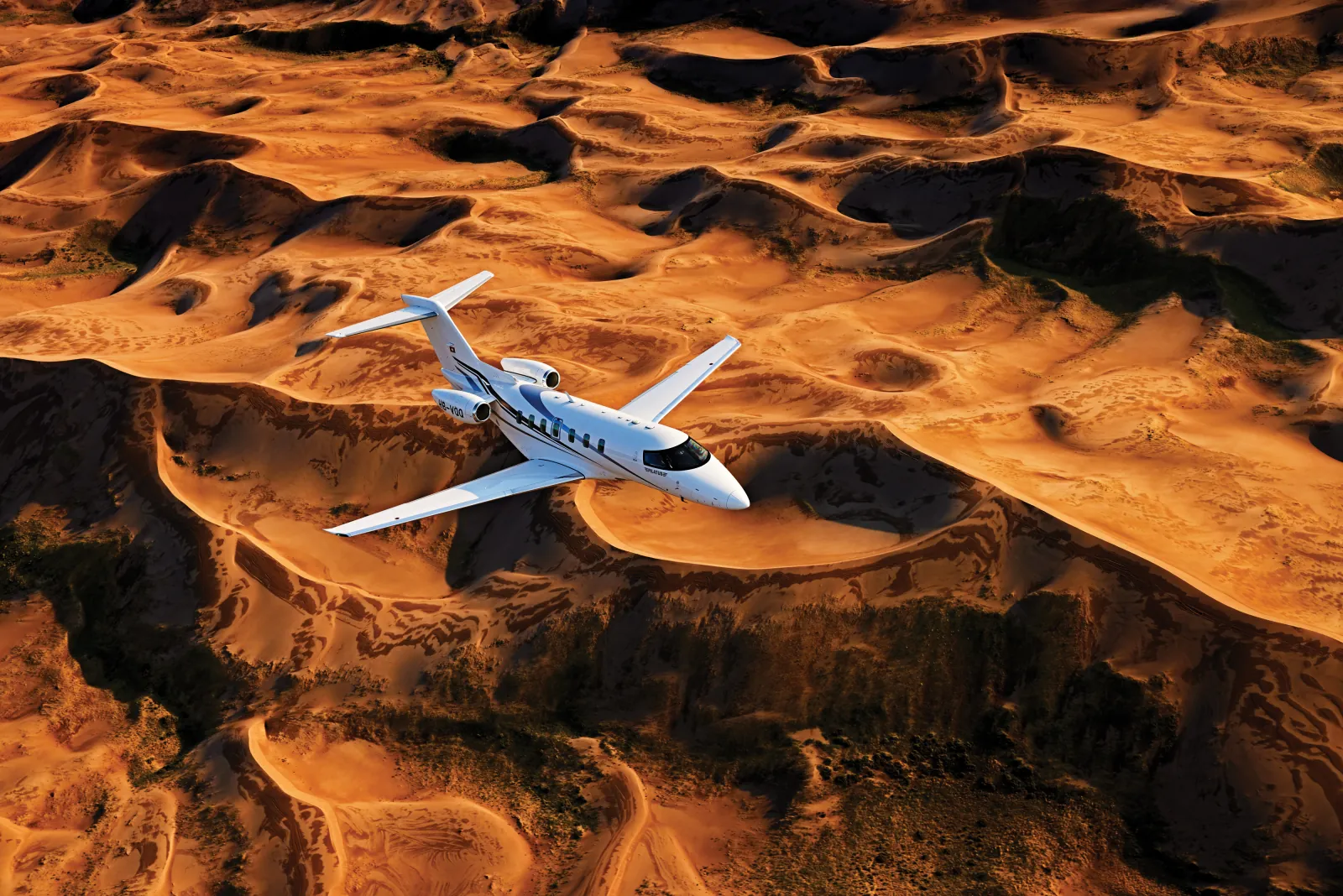 Pilatus PC-24 im Flug über Sanddünen im Abendlicht